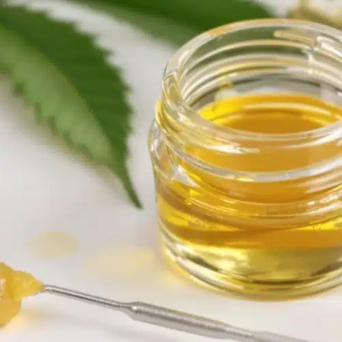 Fresh butane hash oil in a glass container with a dab tool nearby