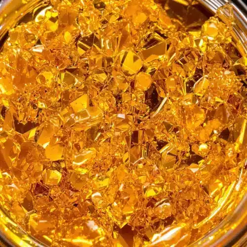 Close-up of golden live resin concentrate in a small dab container.