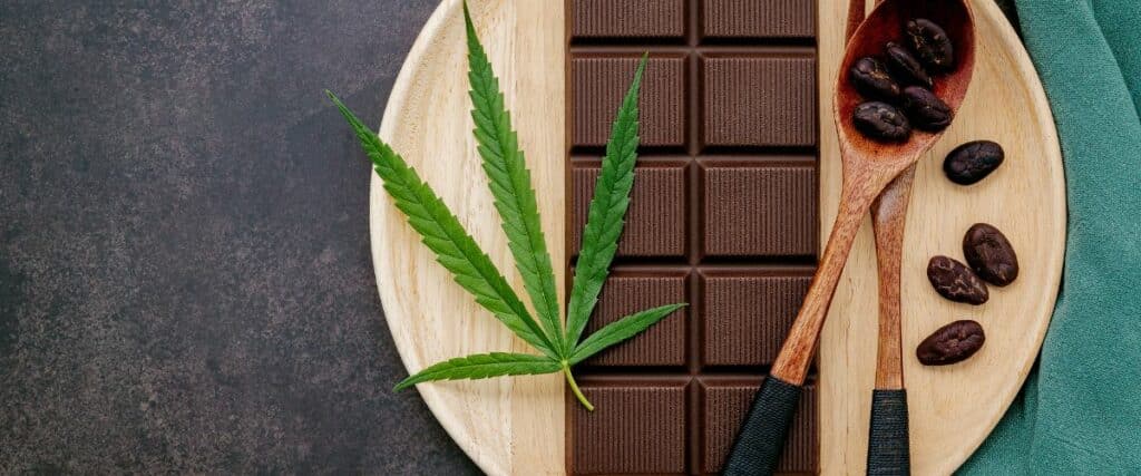 Discover the refined taste of cannabis-infused chocolate bars elegantly presented with a fresh cannabis leaf and coffee beans. This image captures the sophisticated integration of natural elements with artisanal chocolate.