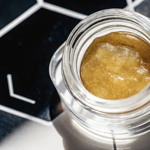 Premium cannabis live resin in glass jar with cannabis leaf background