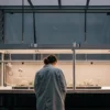 Scientist in a lab coat observing a 3D model of a cannabis plant in a laboratory setting.