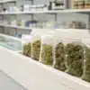 A modern pharmacy counter displaying sealed medical cannabis products in labeled packages, with “sweden weed” visible on the shelf labels.